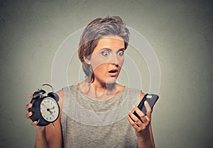 Woman with mobile phone and alarm clock stressed running late
