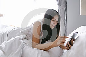 Woman with mobile phone on bed