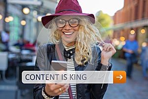 Woman with mobile phone in hands smiling. Content is king.