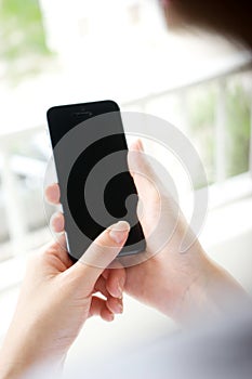 Woman with mobile phone in hands touching on a blank scre