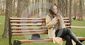 Woman with mobile phone sitting on bench in park and scrolling social network websites enjoying her leisure time. Social networkin