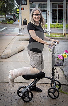 Woman on mobility scooter on street with leg wrapped smiling at camera