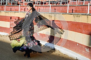 Woman, model of fashion, wearing a dress in a bullring