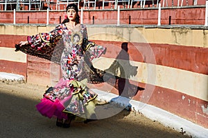 Woman, model of fashion, wearing a dress in a bullring