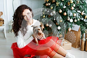 Woman model in a red dress in a photo studio holding a New Year& x27;s gift in her hands