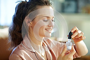Woman at modern home in sunny winter day using cosmetic elixir