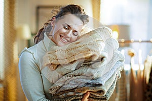 Woman in modern house in sunny winter day holding sweaters