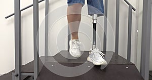 A woman with a modern robotic prosthetic leg is working out in the gym. Physiotherapy rehabilitation that allows a