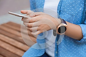 Woman with modern smart watch using phone outdoors, closeup