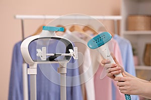 Woman with modern steam iron at home, closeup