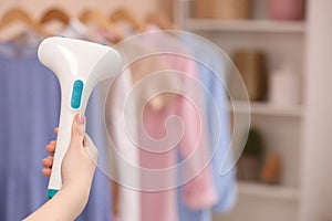 Woman with modern steam iron at home, closeup. Space for text