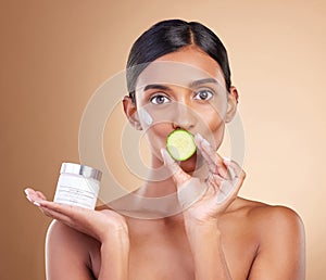 Woman, moisturizer cream and cucumber for natural skincare, beauty and nutrition against studio background. Portrait of