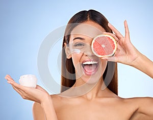 Woman, moisturizer cream and grapefruit for natural skincare beauty and vitamin C against blue studio background