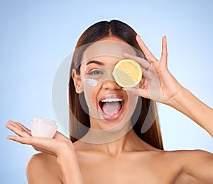 Woman, moisturizer cream and lemon for natural skincare, beauty and vitamin C against blue studio background. Portrait