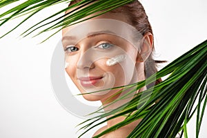 Woman With Moisturizer Cream Posing With Green Leaves, White Background