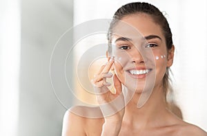 Woman With Moisturizer Dots On Cheeks Applying Facial Cream Indoor