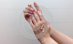 Woman moisturizing her hand with cosmetic cream.