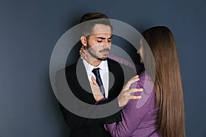 Woman molesting her male colleague on dark background.