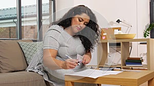 Woman with money, papers and calculator at home