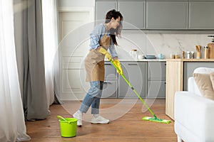 Woman mopping floor in bright kitchen interior