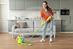 Woman mopping floor with bright smile and bucket