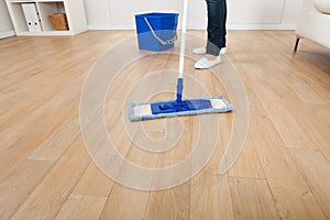 Woman mopping hardwood floor at home
