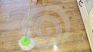 Woman mopping the kitchen floor with mop and bucket. Cleaning parquet floors in the living room