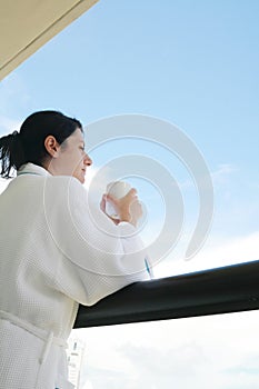 Woman with morning coffee looking through balcony