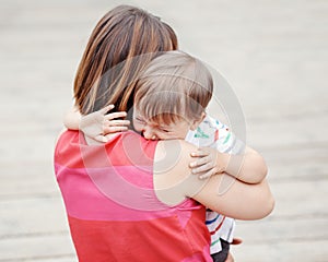 Woman mother comforting her crying little toddler boy son