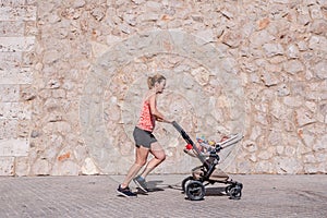 Woman, mother doing fitness pushing the baby stroller