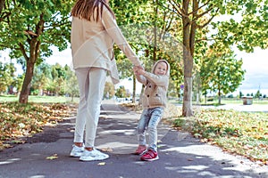 Woman mother walks with her child, little son, boy of 4-5 years old, autumn day on street in park, happy people playing