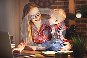 Woman mother working with a baby at home behind a computer