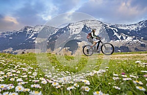 Woman on mountain bike in snow capped Allgaeu Alps, Germany