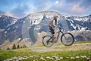 Woman on mountain bike in snow capped Allgaeu Alps, Germany