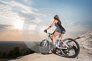 Woman with the mountain bike under a sky at sunset