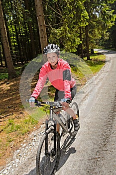 Woman mountain biking in sunny forest smiling