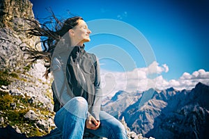 Woman on mountain hike resting, her hair blowing in wind