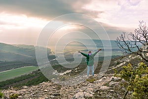 woman on mountain peak looking at beautiful mountain valley in fog at sunset. Landscape with sporty young woman, foggy