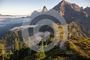 A woman on a mountain trail taking a photo of the view