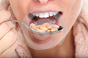 Woman mouth eating pills.