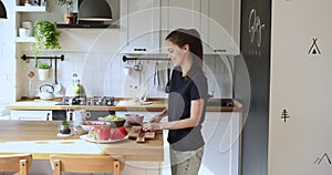 Woman moves to music while preparing vegetable salad in kitchen