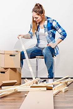 Woman moving into apartment assembly furniture.