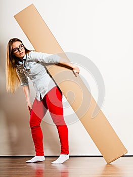 Woman moving into apartment carrying heavy box.