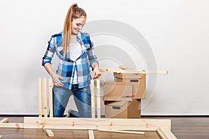 Woman moving in assembly furniture at new home.