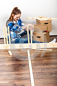 Woman moving in assembly furniture at new home.