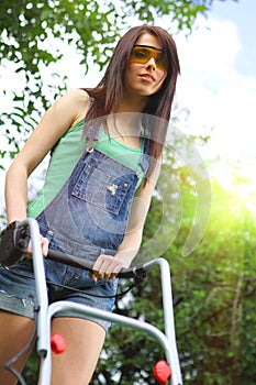 Woman mowing grass with lawnmower