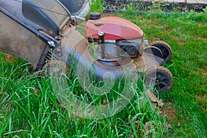 In woman mowing a green lawn near the home with a lawn mower in the backyard