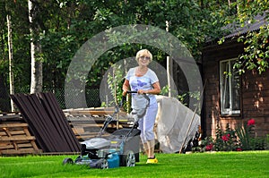 Woman is mowing her lawn with lawn mower