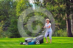 Woman is mowing her lawn with lawn mower