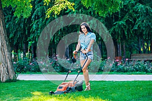 Woman mowing lawn in residential back garden on